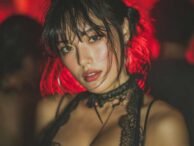 Glamorous woman with dark hair and lace choker under red lighting. Malaysia Escort.