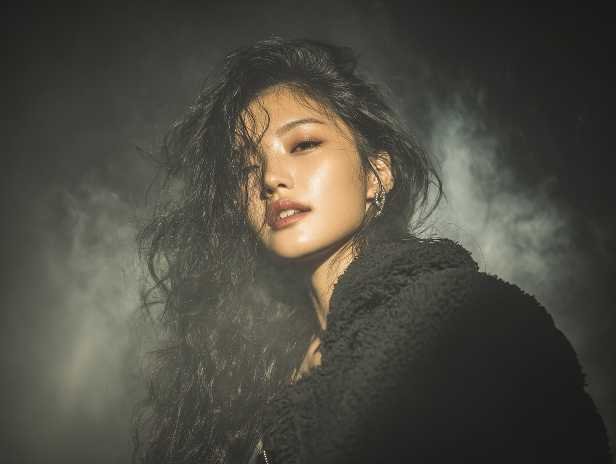 Portrait of a woman with dark, wavy hair in a dramatic, smoky setting.