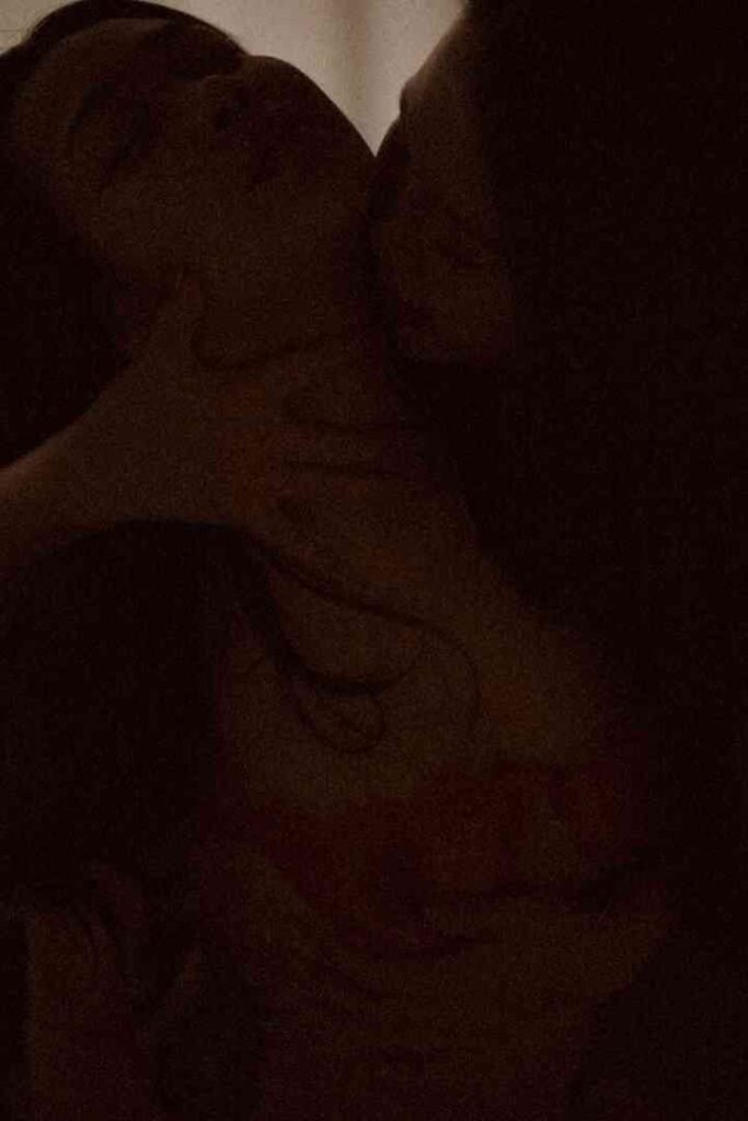 Viola and Cici embracing intimately in dim lighting.
