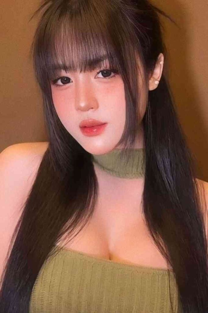 Young Malay woman with long dark hair and bangs, wearing a green top.