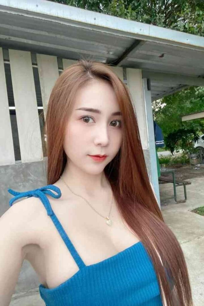 Amy, a 23-year-old Thai woman with long brown hair, wearing a blue top.