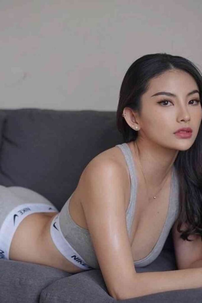 Dewi, 22yo, in athletic wear, posing on a couch