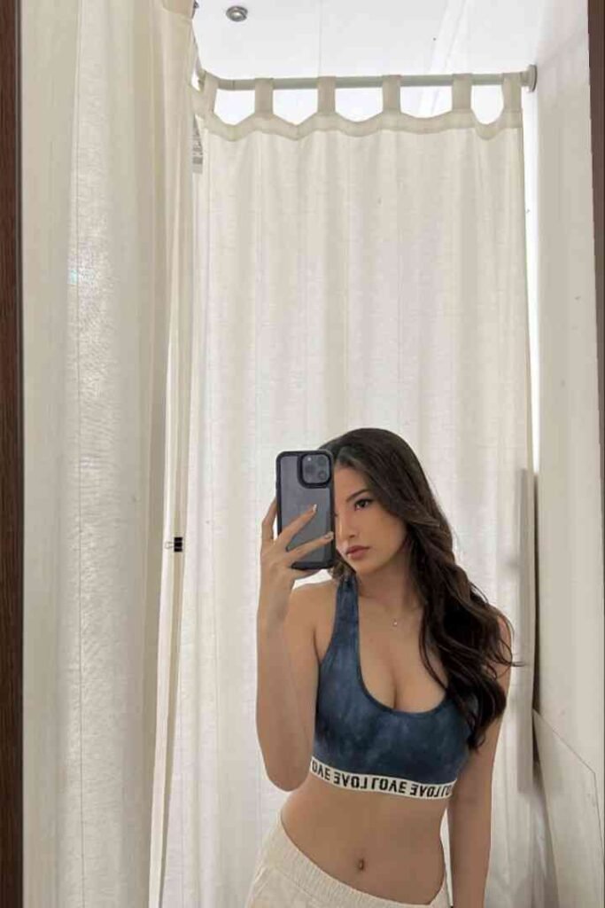 Dewi, local Malay escort in KL, takes selfie in front of white curtain