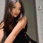Brunette woman in black lace dress posing for the camera in a modern room