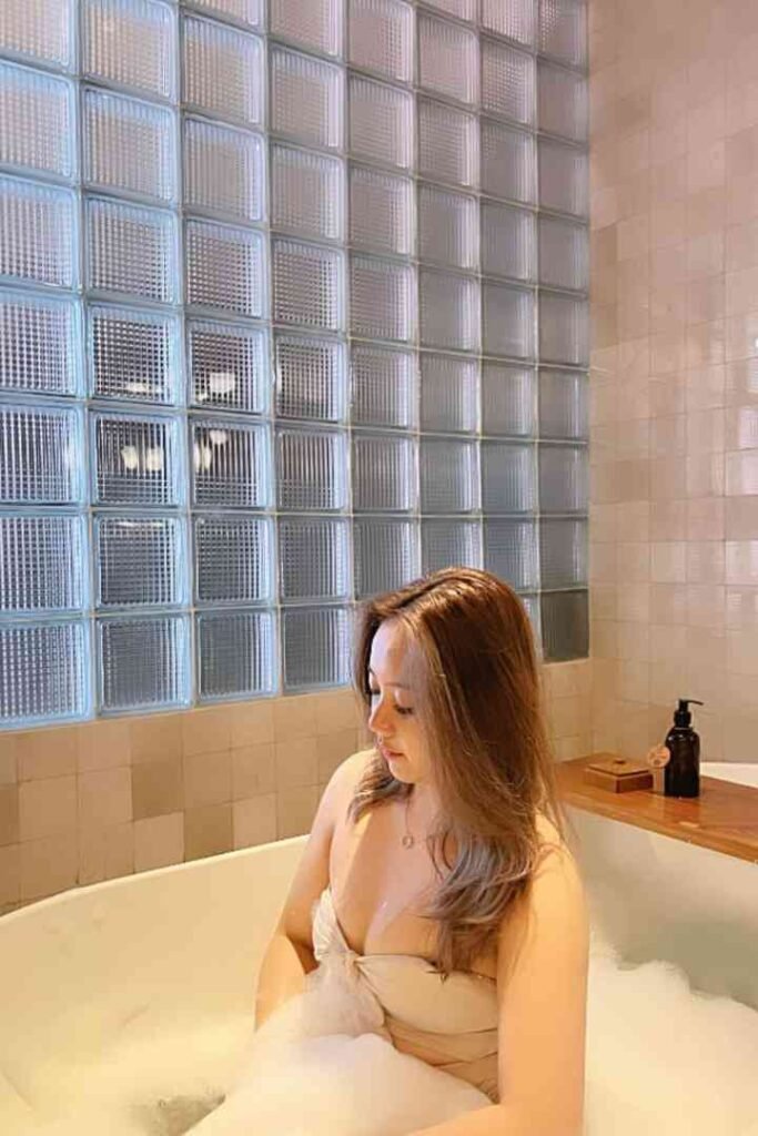 Local Malay escort Fitri in bathtub with bubbles, wearing a white dress