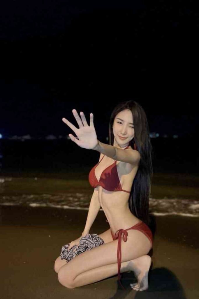 Woman in red bikini waving on beach at night