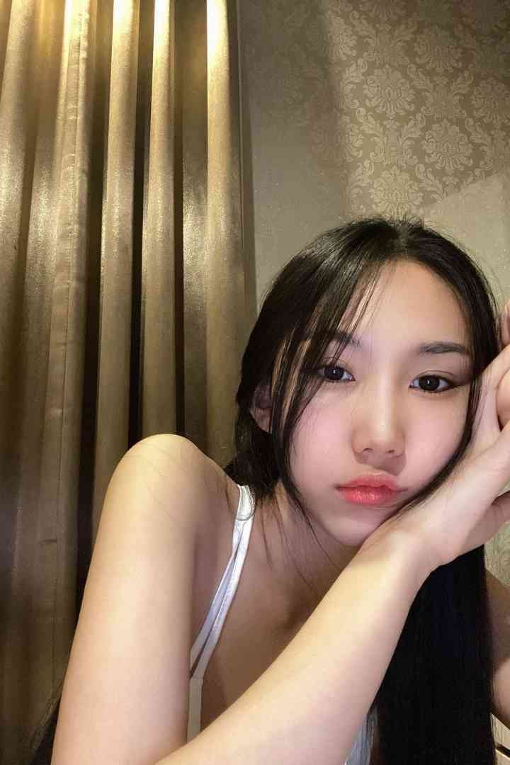 Asian woman with black hair and red lipstick in a room with gold curtains