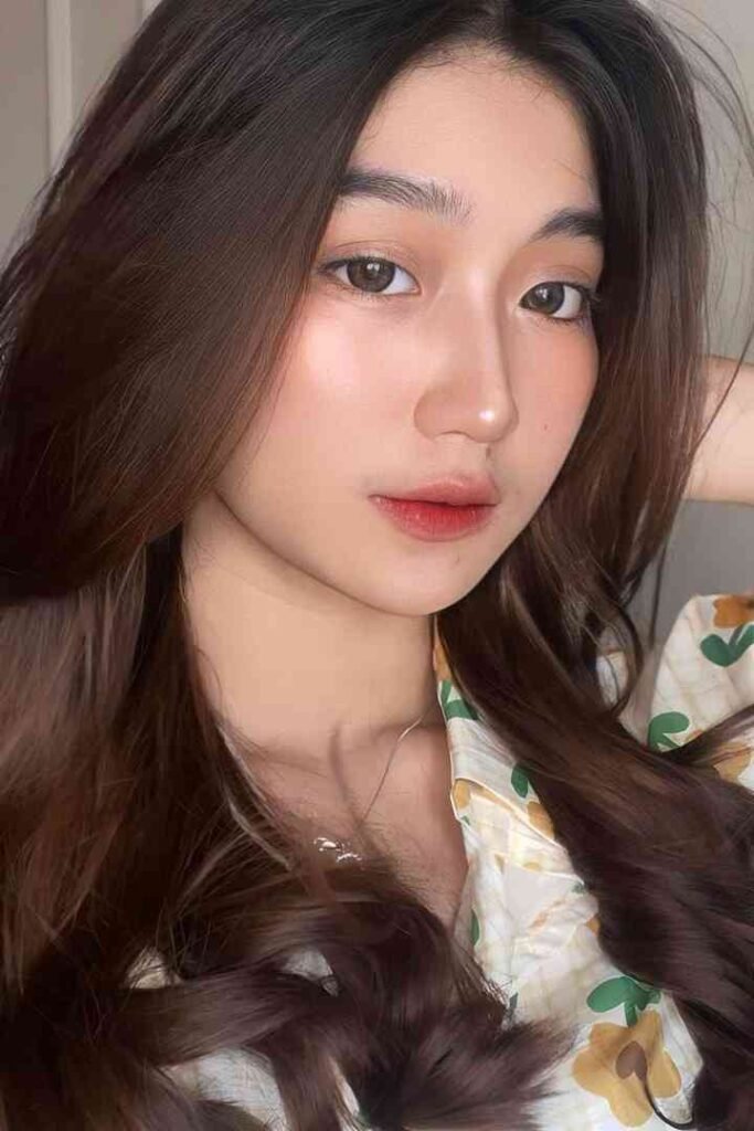 Young Malay woman with long brown hair, floral shirt, and red lips