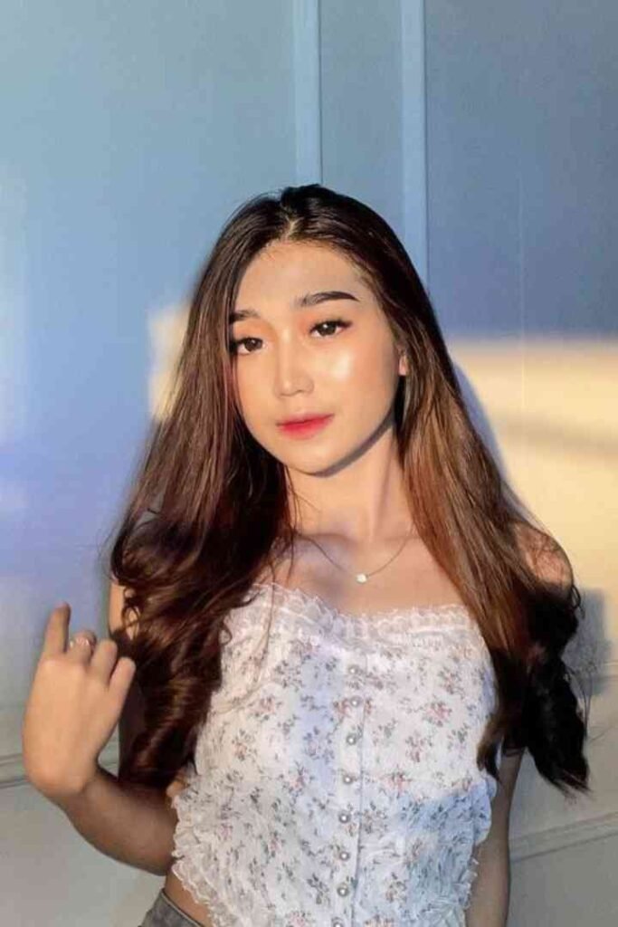 Young Malay woman in floral top, long brown hair, posing indoors