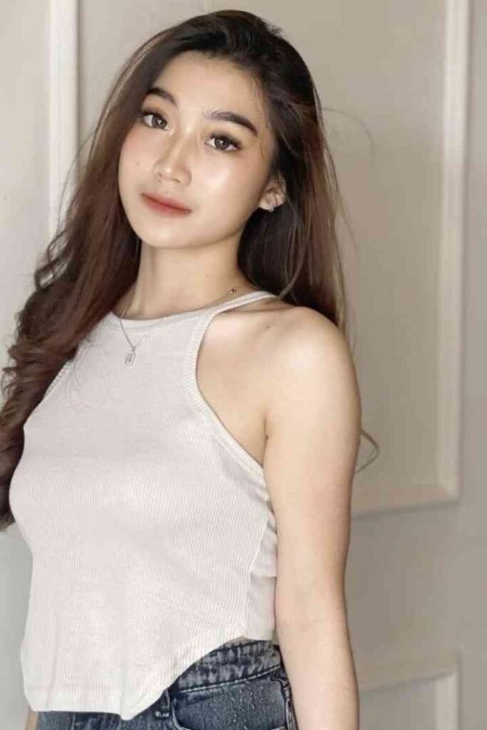 Young woman with long brown hair wearing a white tank top