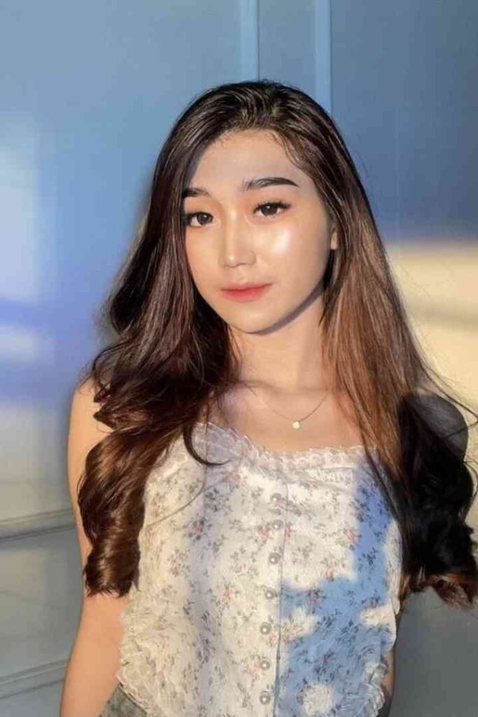 Young Malay woman with long hair in floral top, smiling for the camera