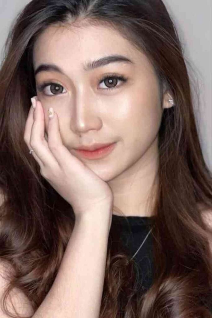 Close-up of smiling young Malay woman with long hair touching her face