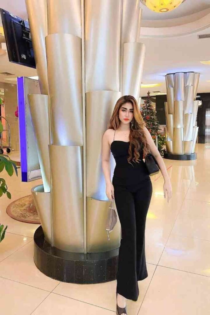 Woman in black jumpsuit standing in lobby next to large metallic sculpture