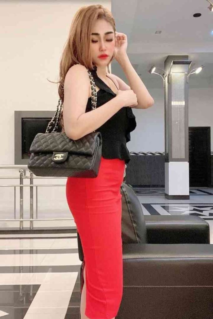 Woman in black top and red skirt with Chanel bag