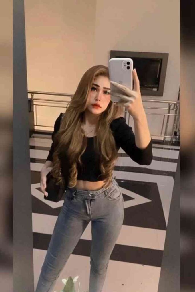 Woman in crop top and jeans taking a mirror selfie