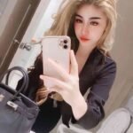 Woman in black blazer taking a mirror selfie with a handbag