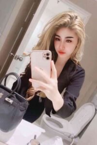 Woman in black blazer taking a mirror selfie with a handbag