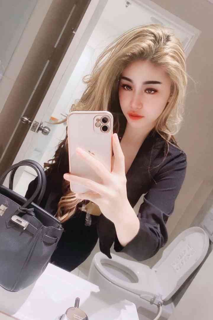 Woman in black blazer taking a mirror selfie with a handbag