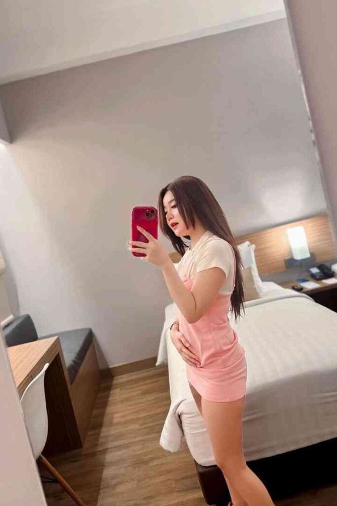 Young woman in pink dress taking selfie in hotel room