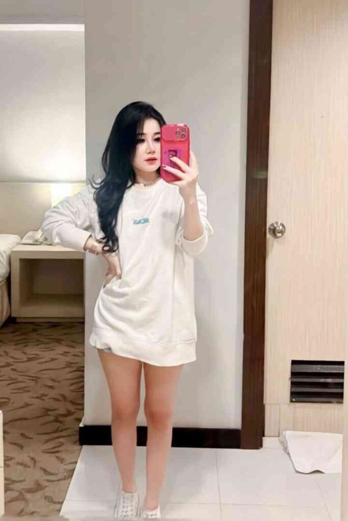Woman in white shirt taking selfie in bathroom
