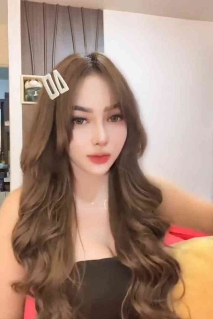 Malay call girl Sindy with long brown hair in a black dress posing for a photo