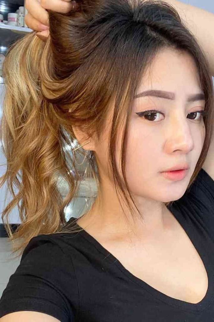 Young woman with brown and blonde ombre ponytail, wearing black shirt