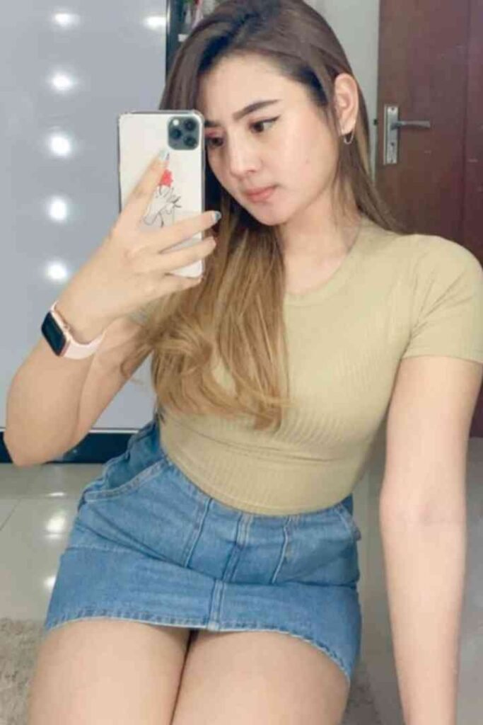 Tasya, a 165cm beauty, poses for a mirror selfie in a denim skirt and beige top.