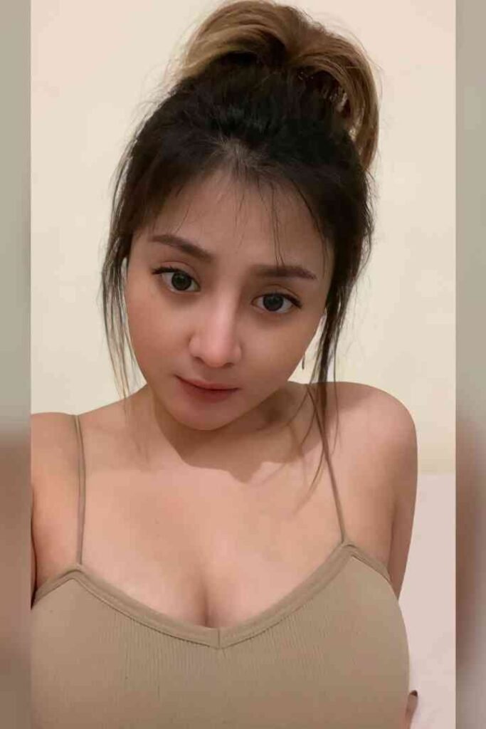 Tasya, local Malay escort, smiling in a beige tank top with exposed shoulders
