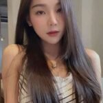 Woman with long hair wearing a black and white striped top and necklace