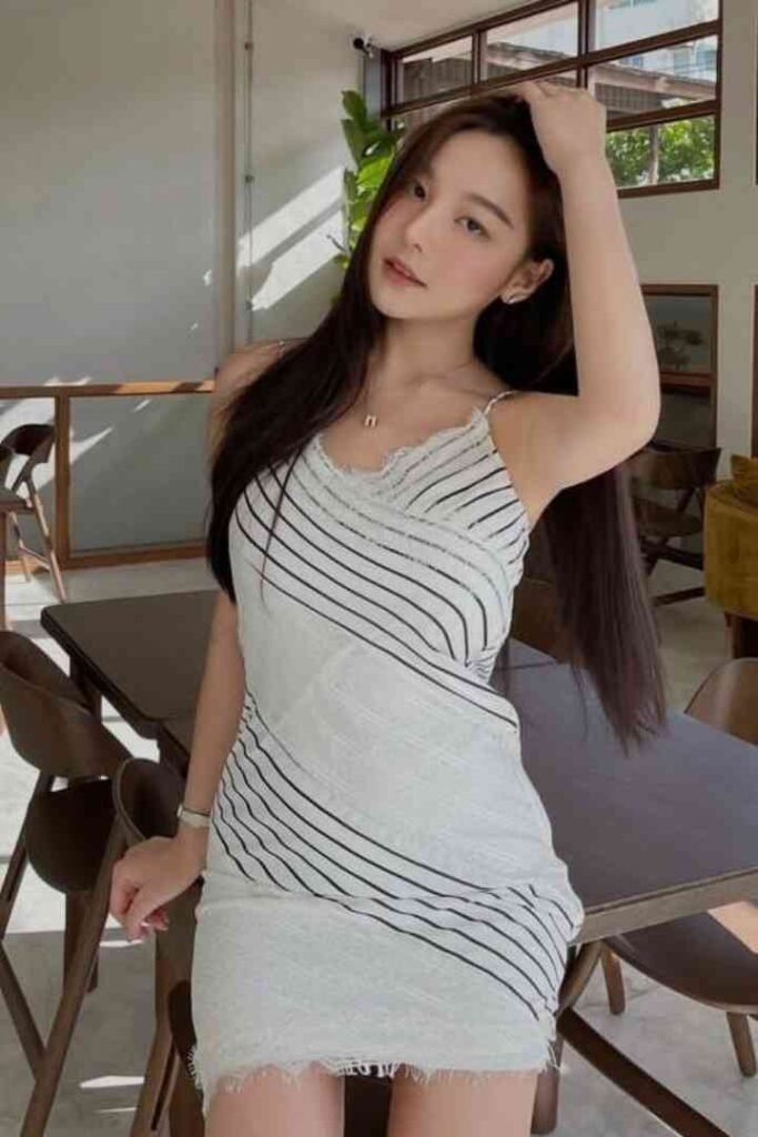 Yuki, a 22-year-old Chinese woman with long dark hair, wearing a white and black striped dress.